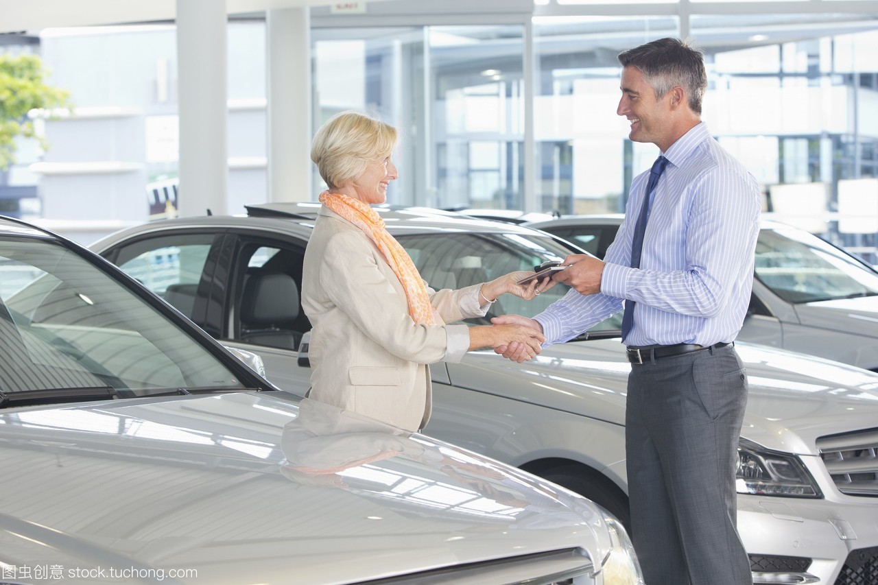 销售人员和顾客在汽车经销商展厅中握手